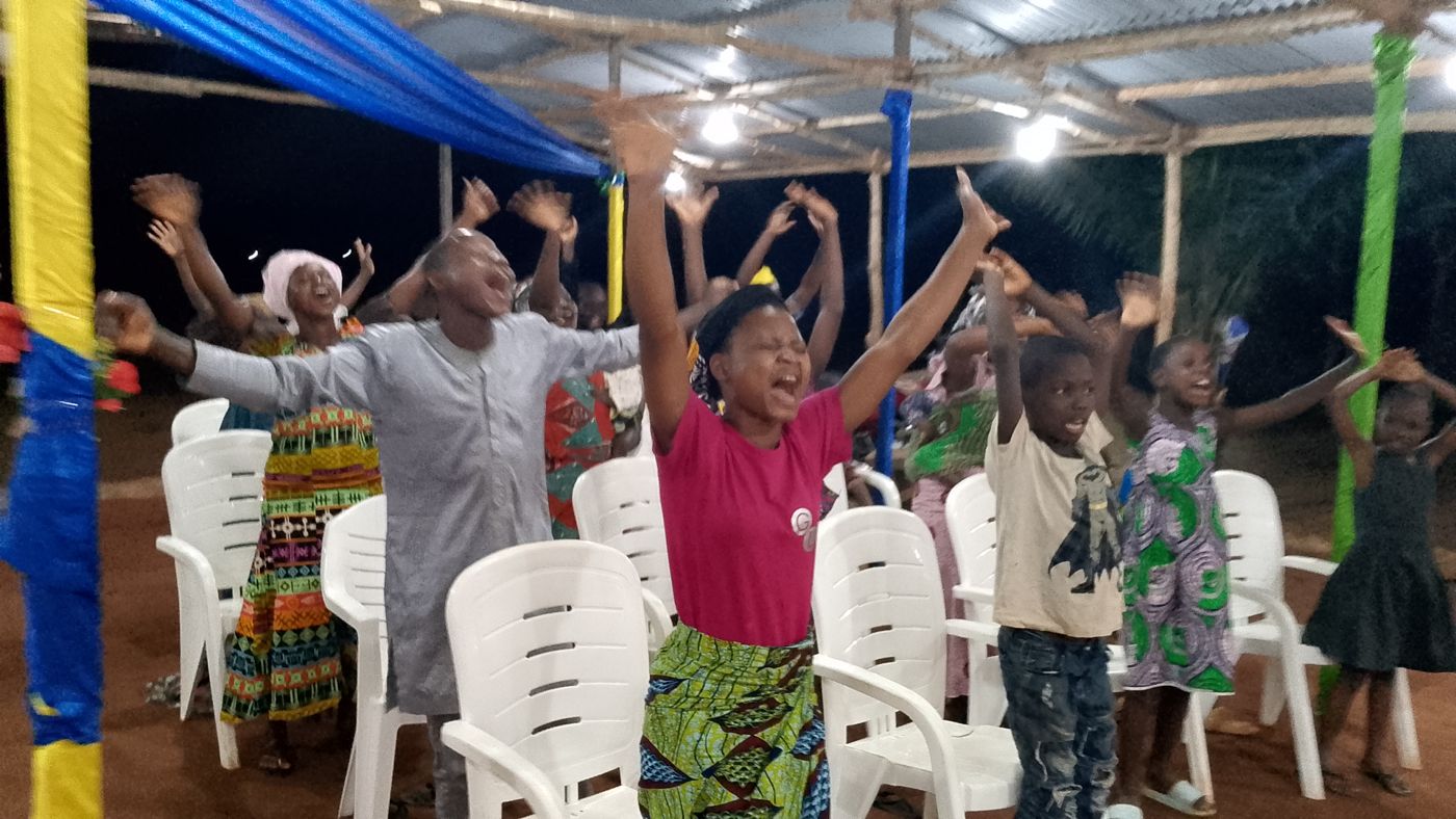 Fidèles en adoration, mains levées, lors d'une veillée au camp